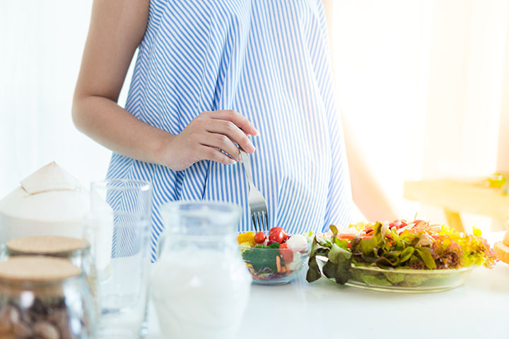 Pregnant women Put on a blue dress. She is eating breakfast salad. For the health and for the baby in her belly. Contains coconut, milk and salad dressed on the table.